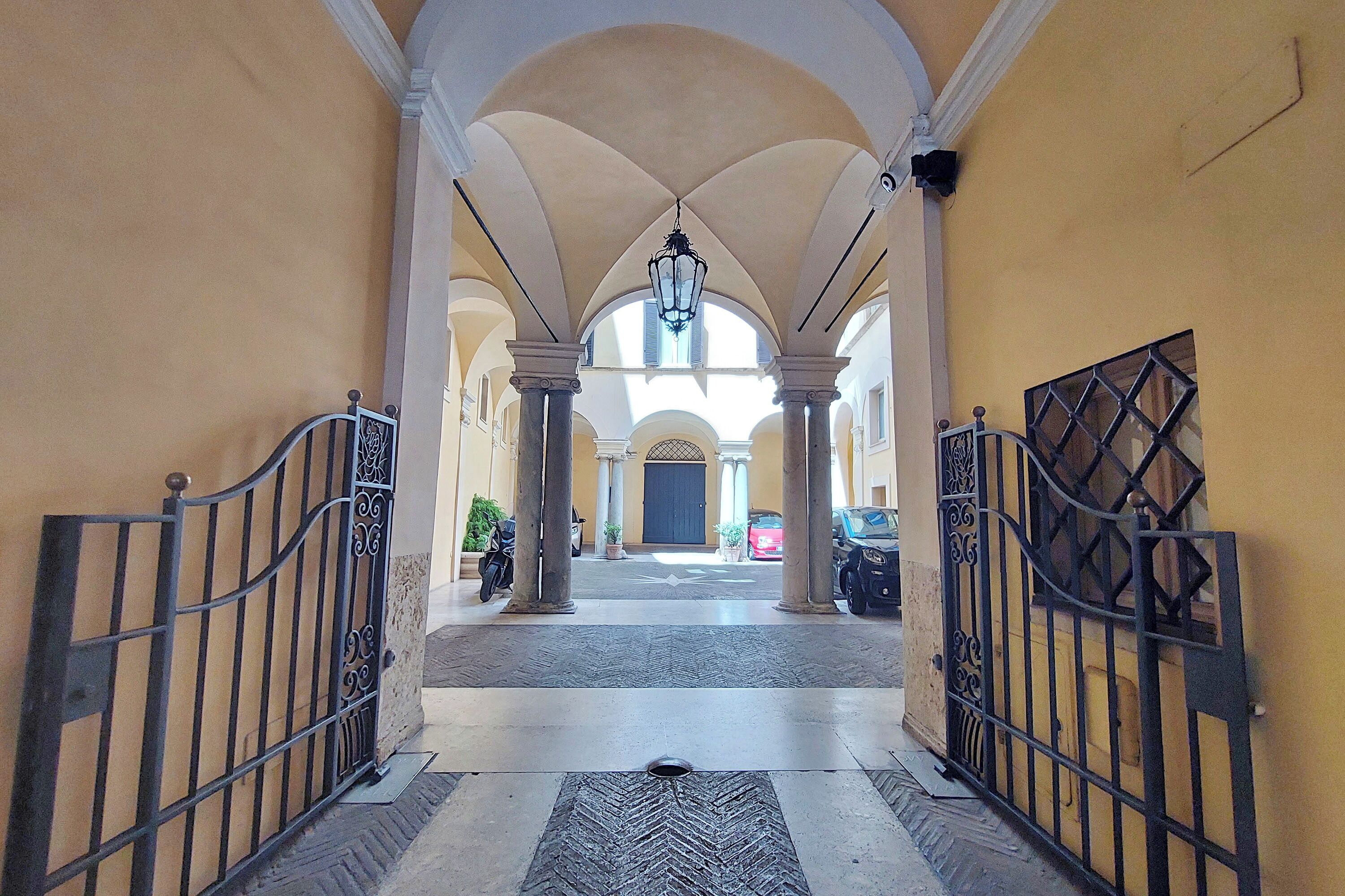 A corridor with arches, a central light fixture, and a gated entrance.