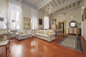 A spacious living room with a chandelier, white sofas, and a patterned rug. - Lavish apartment in historical building - Palazzo Boncompagni Corcos (Roma)