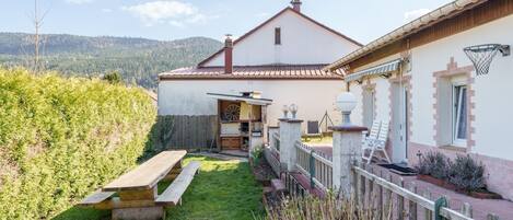 A house with a patio, a wooden bench, a basketball hoop, and a view of the mountains.