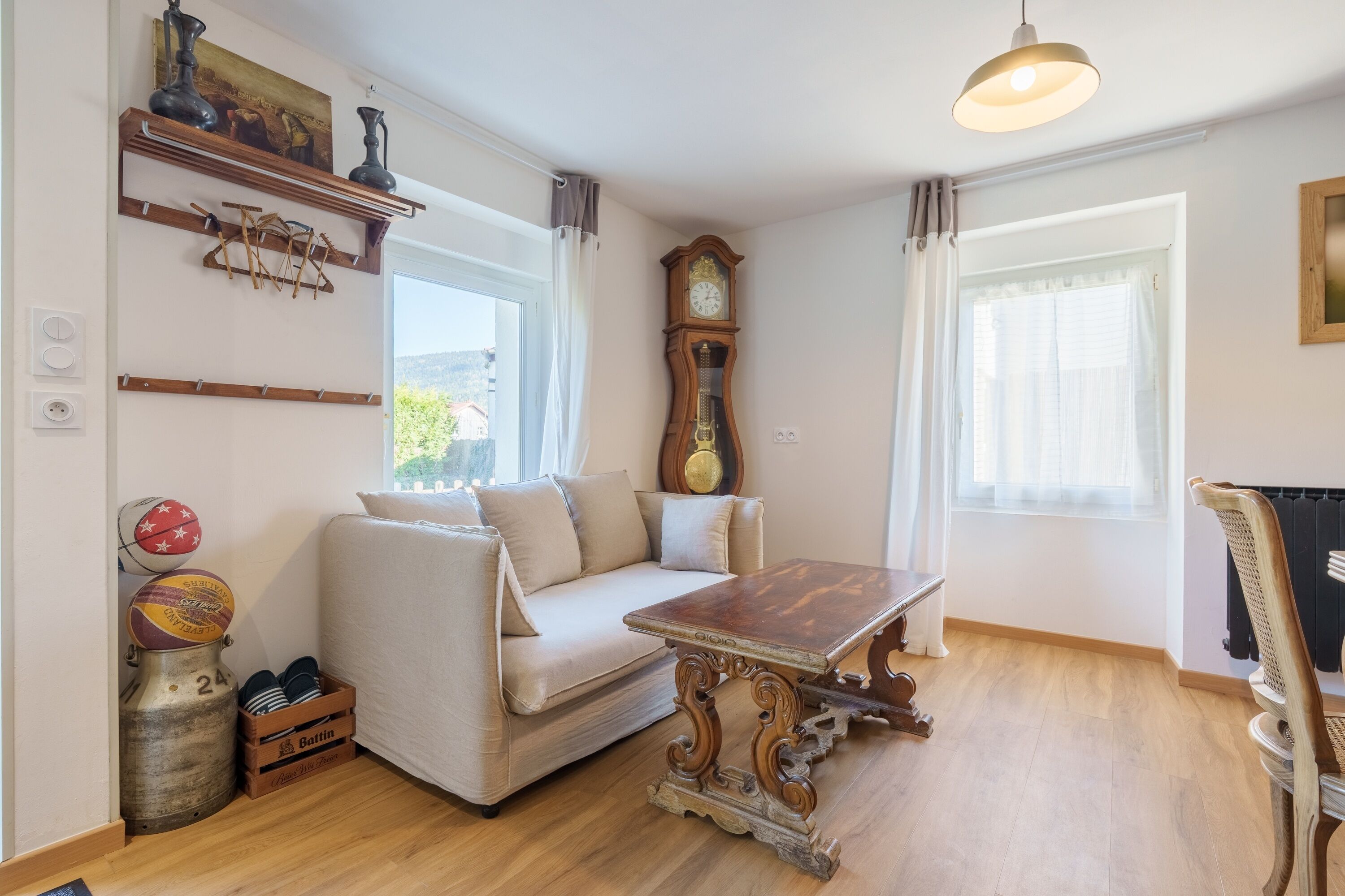 Una sala de estar con un sofá, una mesa de madera, un reloj y un radiador.