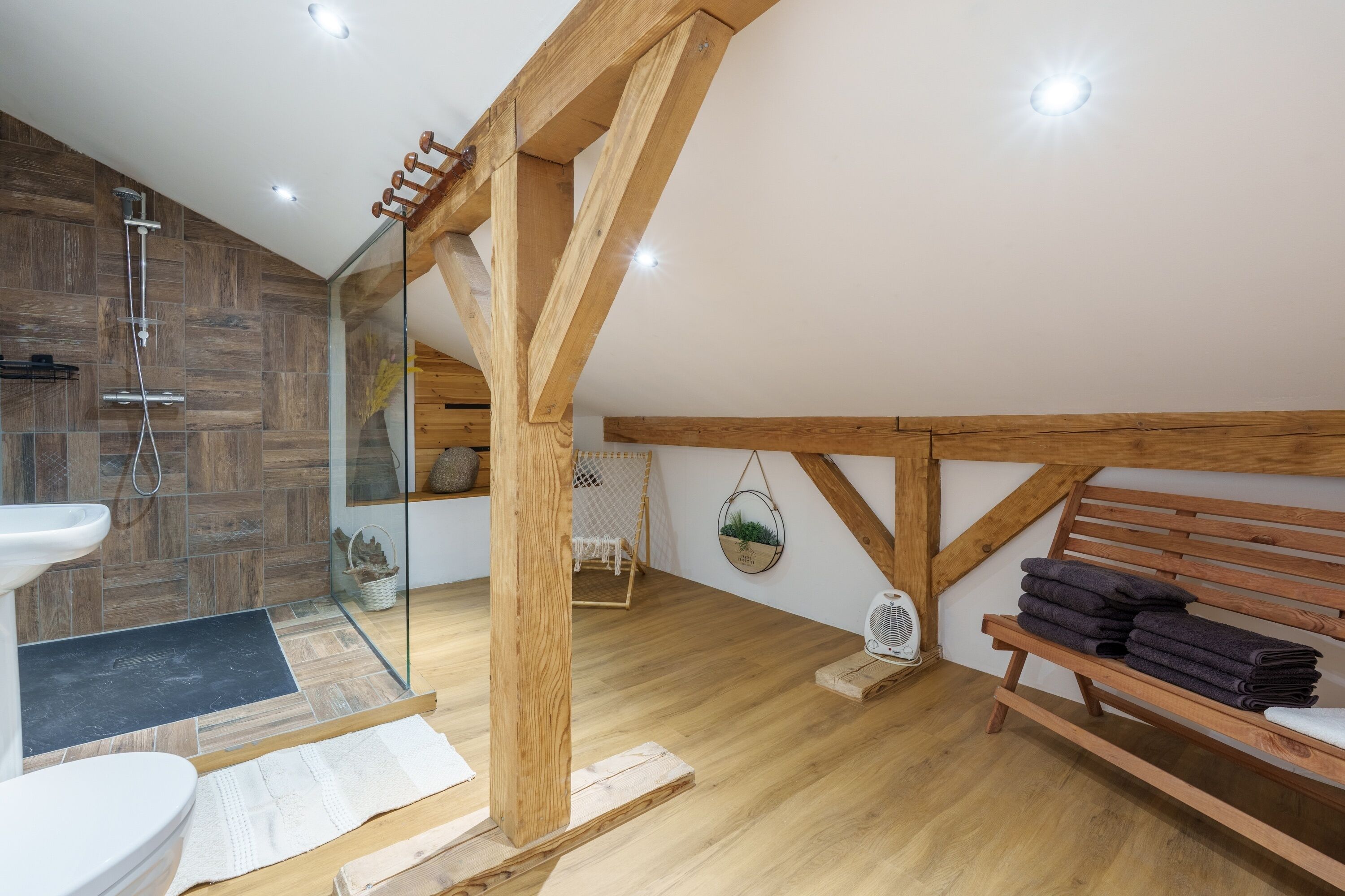 Une salle de bain moderne avec une douche, un lavabo et des poutres en bois.
