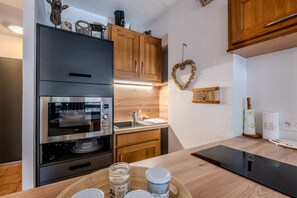 Eine kompakte Küche mit Einbauofen, Spüle, Holzausstattung und einer Wanddekoration in Herzform.