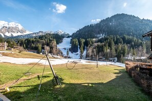 Eine Berglandschaft mit blauem Himmel, einer Skipiste und einem Gebäude mit schrägem Dach.