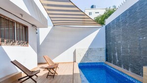 A modern outdoor pool area with two lounge chairs, a wooden deck, and a stone wall. - 1 King, 3 Twin bed, Pool & 2 parking | 3BR2br 7ppl (Monterrey)