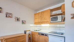 Een keuken met houten kastjes, een magnetron, een vaatwasser en een spoelbak.