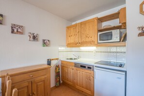 Eine Küche mit Holzausstattung, einer Mikrowelle, einem Geschirrspüler und einem Spülbecken.