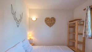 Een slaapkamer met een bed, een wandlamp, een hartvormige decoratie en een houten wandplank.