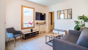 Una sala moderna con sofá, sillón, televisor y una mesita.