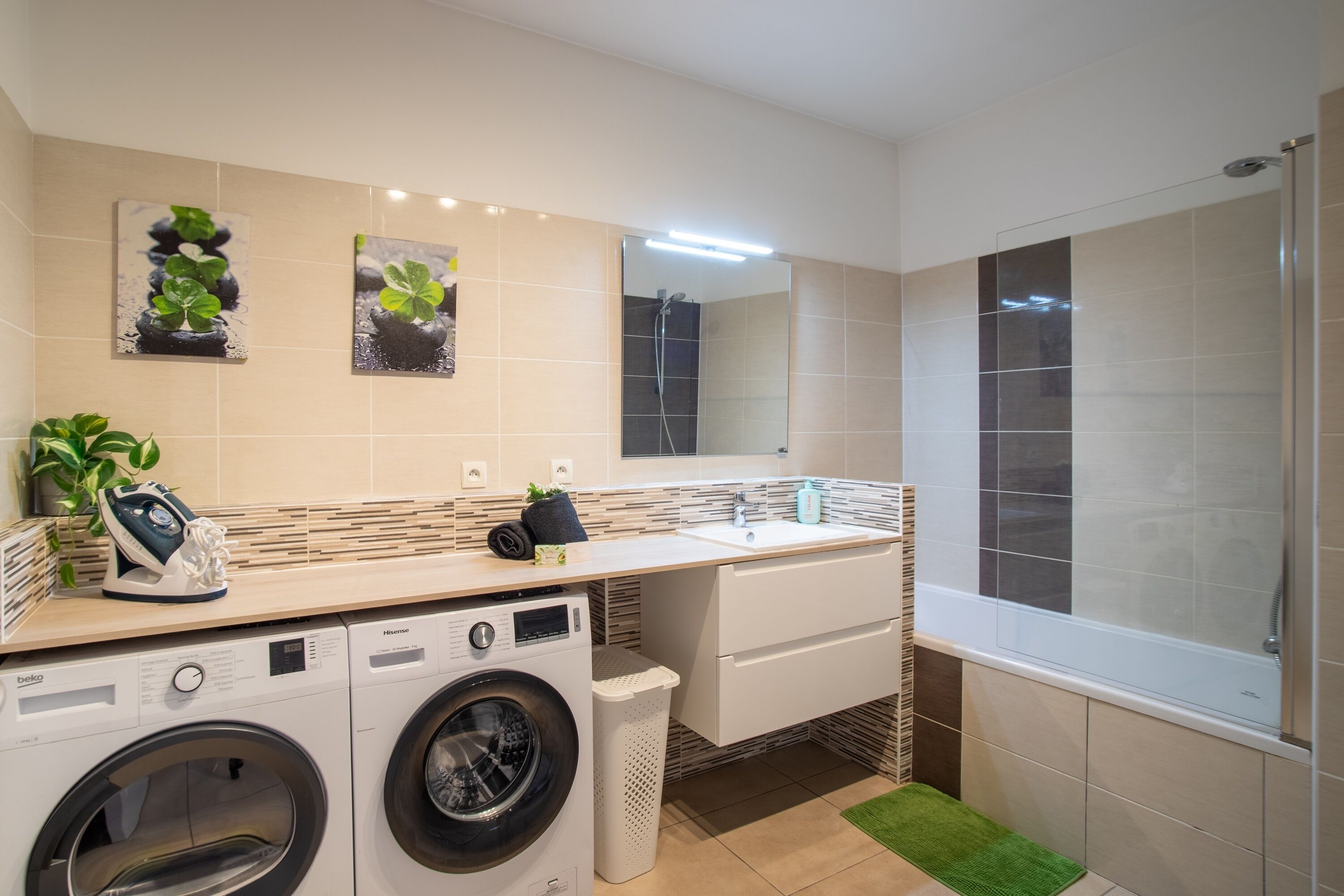 A modern bathroom with a dual sink, a large mirror, a washing machine, and a shower enclosure.