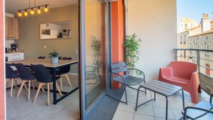 Un balcón con zona de comedor, sillas y una mesa.