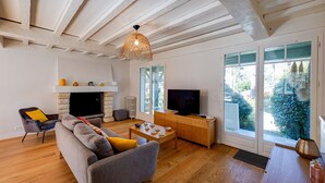Een moderne woonkamer met een open haard, bank, televisie en grote ramen.