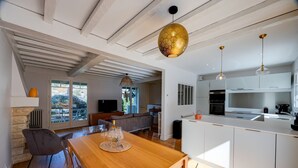Een moderne keuken met witte kasten, een houten eettafel en hanglampen.
