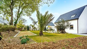 Ett bostadsområde med hus, en gräsmatta och en trädgård med täckbark och växter.