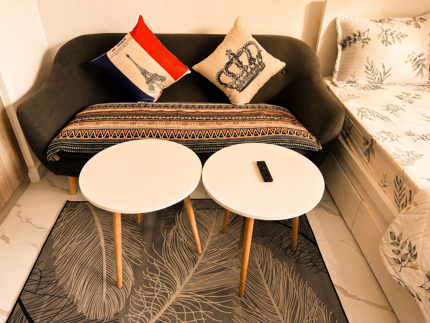 Ein modernes Wohnzimmer mit einer Couch, zwei runden Tischen und dekorativen Kissen.