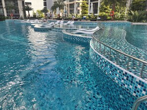 Piscina com bordas revestidas, espreguiçadeiras e guarda-sóis.