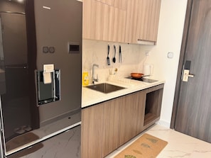 A modern kitchen with a built-in refrigerator, a sink, and wooden cabinets. - Vinhomes Grand Park Homestay - Opus One (Ho Chi Minh City)
