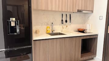 A modern kitchen with a black refrigerator, wooden cabinets, a marble backsplash, and a built-in oven.