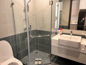 A modern bathroom with a glass-enclosed shower, a white sink, and a toilet. - Vinhomes Grand Park Homestay - Opus One (Ho Chi Minh City)
