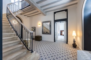 A staircase with black iron railings, a patterned floor, a mirror, a lamp, and a radiator. - Holiday Home “Le Domaine De Peyvideau” with Private Pool, Terrace, and Wi-Fi (Carignan-de-Bordeaux)