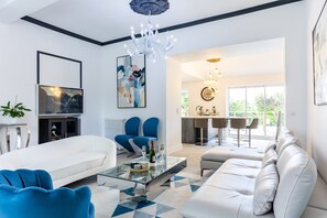 A modern living room with a sofa, chairs, a glass coffee table, and a chandelier. - Holiday Home “Le Domaine De Peyvideau” with Private Pool, Terrace, and Wi-Fi (Carignan-de-Bordeaux)