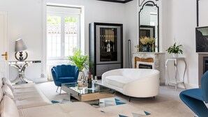 Una sala de estar moderna con un sofá, una mesa de centro, un sillón azul, una chimenea y un espejo grande.