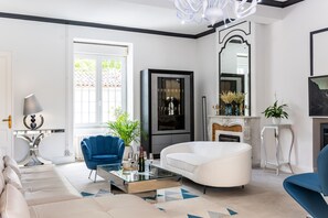 A modern living room with a sofa, a coffee table, a blue armchair, a fireplace, and a large mirror. - Holiday Home “Le Domaine De Peyvideau” with Private Pool, Terrace, and Wi-Fi (Carignan-de-Bordeaux)