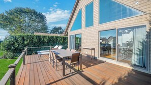 A modern house with a wooden deck, a dining area, and large windows.