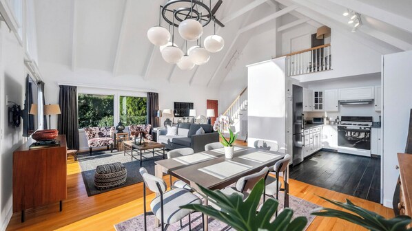 A spacious living area with a dining table, sofas, and a kitchen in the background.