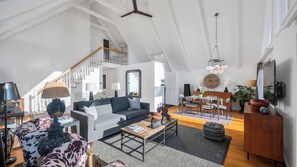 Un loft espacioso con techo alto, una escalera, una zona de comedor y una sala de estar amoblada con sofás y una mesa de centro.