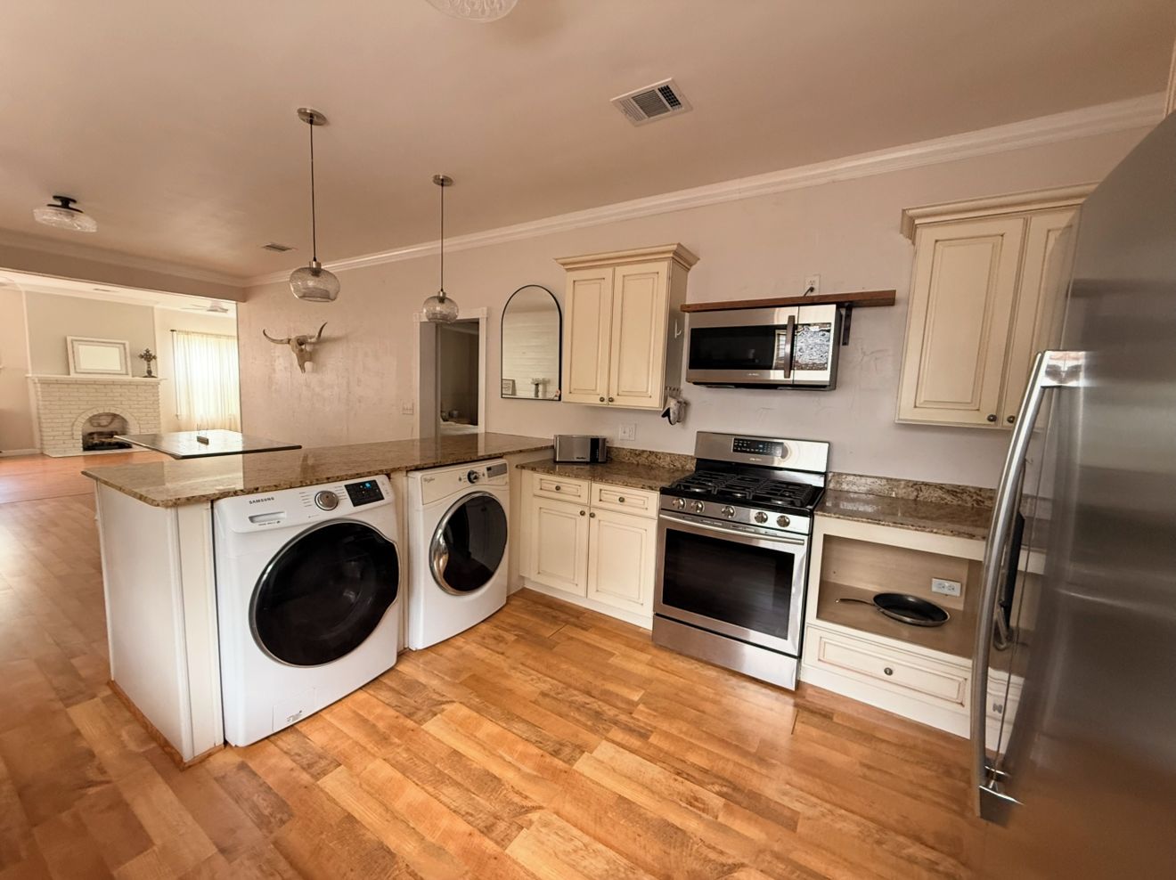 A kitchen with a built-in washer and dryer, stainless steel appliances, and wooden flooring.