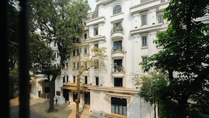 A multi-story building with balconies, large windows, and a tree-lined street. - Moc Vien Homestay Train Street (Hanoi)