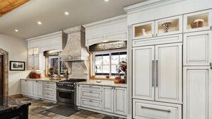 A spacious kitchen with white cabinetry, a large stove, and a stone backsplash. - Whitestone Ranch | Luxury Lakefront Estate Near Muskoka (Sleeps 24) (Dunchurch)