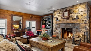 A rustic interior with a stone fireplace, wooden furniture, and a large mirror. - Whitestone Ranch | Luxury Lakefront Estate Near Muskoka (Sleeps 24) (Dunchurch)