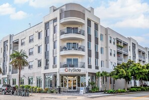 Ein mehrstöckiges Hotel mit Balkonen, einem Laden und einem Parkplatz.