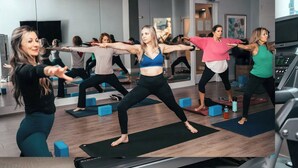 Un groupe de personnes fait de l’exercice dans une salle de sport, en utilisant des tapis de sol, des poids et un tapis de course.