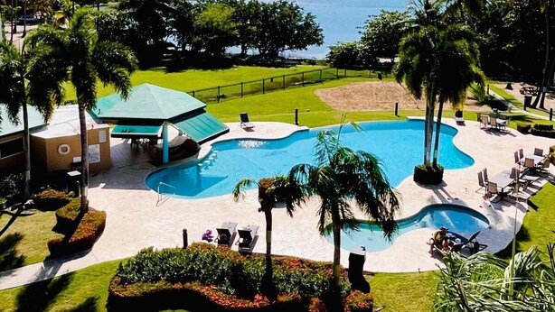Ein Resort mit großem Pool, Palmen und Blick auf den Ozean.
