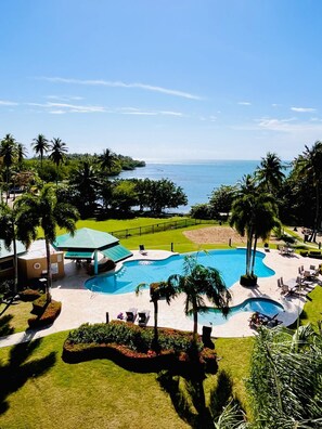 Un resort con una amplia piscina, palmeras y vista al océano.
