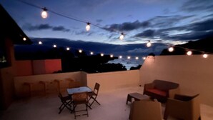 Eine Terrasse im Freien mit Lichterketten, einem Tisch und Stühlen.