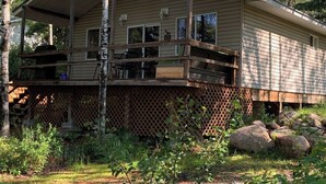 A two-story cabin with a covered porch, a chimney, and a wooden deck.