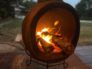 En vedeldad kamin med lågor, placerad på ett stativ utomhus.