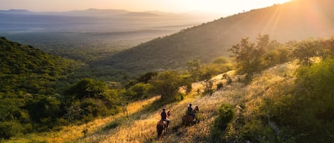 A mountainous landscape with two people riding horses.