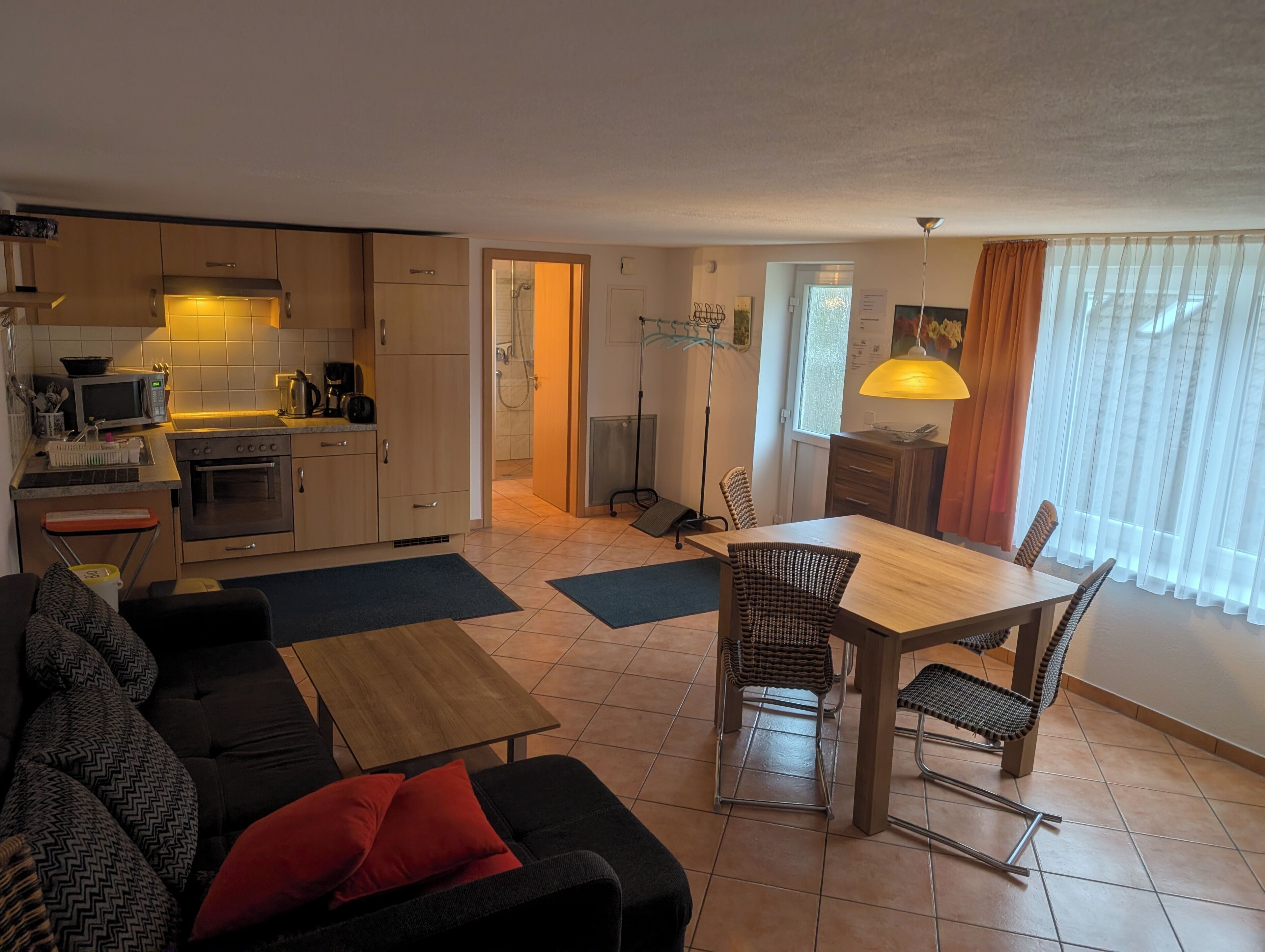 Un espace de vie compact comprenant un coin cuisine, un coin repas et un espace détente avec un canapé et des fauteuils.