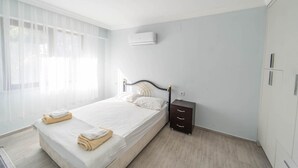 Une chambre à coucher comprenant un lit, une table de chevet et un appareil de climatisation.