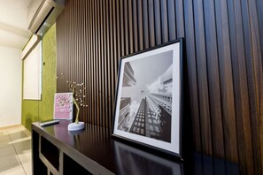 Un comptoir d’accueil orné d’une photographie en noir et blanc encadrée, d’un petit arbre décoratif et d’un mur composé de lattes de bois verticales.