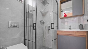 Ein modernes Badezimmer mit Duschkabine aus Glas, Toilette und Waschtisch mit Spiegel.