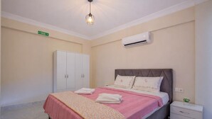 Ein Schlafzimmer mit Bett, Nachttisch, Kleiderschrank und Klimaanlage.