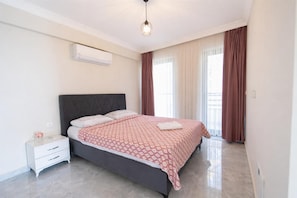 Un dormitorio con una cama, una mesita de noche blanca y una lámpara en el techo.