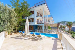A modern multi-story building with a swimming pool, outdoor seating, and a view of the surrounding landscape. - Villa Kuluhana With 3 Bedrooms and 3 Bathrooms (Kaş)