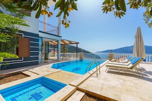 A swimming pool with lounge chairs and a view of the sea. - Villa Kuluhana With 3 Bedrooms and 3 Bathrooms (Kaş)