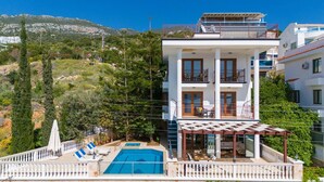 A two-story building with a pool, outdoor seating, and a view of a mountainous landscape. - Villa Kuluhana With 3 Bedrooms and 3 Bathrooms (Kaş)